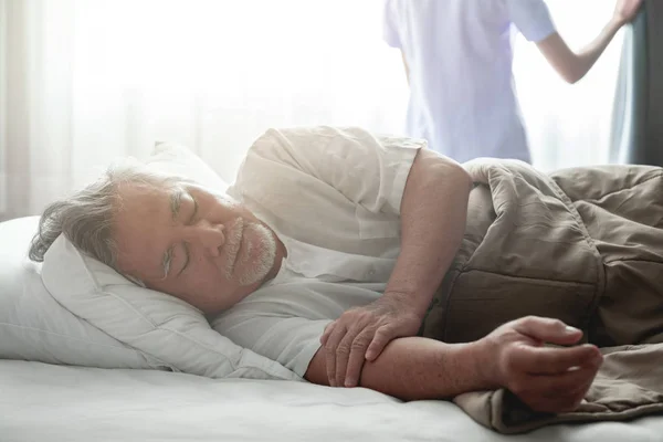 Senior man sleeping in bed and nurse open curtain. Old asian man and beautiful asian nurse woman in bedroom and open curtain. Senior home service concept. Close up shot.