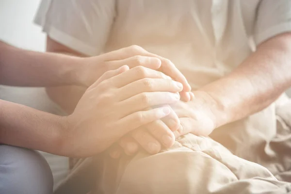 El rahatlatıcı. Genç tutan yaşlı adamın elini hemşire. Üst düzey bakım, bakım alıcı ve üst düzey emeklilik ev hizmet anlayışı. Atış kapatın.