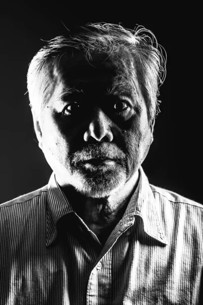Rugged old man portrait. Black and white of old asian man with white beard. Dramatic lighting.