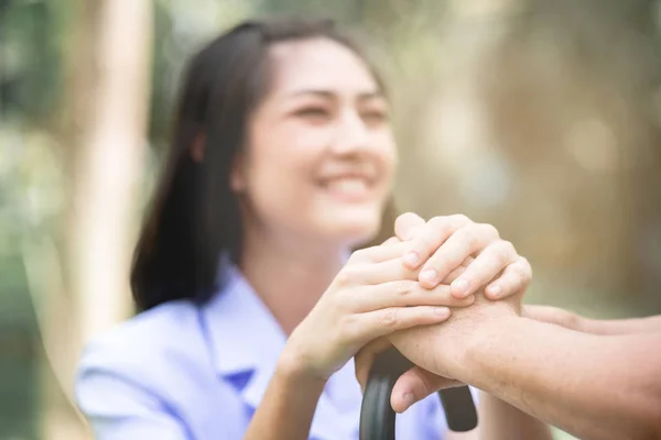 Tröstande Hand Ung Sjuksköterska Innehav Gubbens Hand Utomhus Trädgård Sitter — Stockfoto