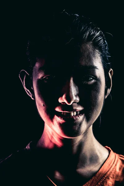 Halloween zombie girl portrait. Asian woman in orange t-shirt, dramatic lighting. For scary halloween concept.