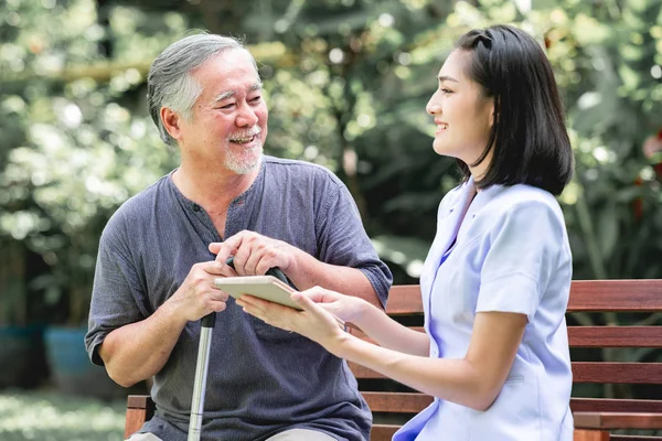 Infirmière Avec Patient Assis Sur Banc Regardant Ensemble Tablette Asiatique — Photo