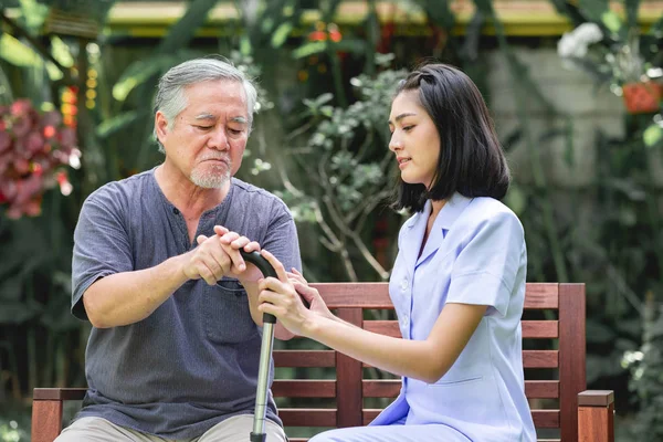 护士与病人坐在板凳上一起说话 亚裔老人和年轻女子坐在一起说话 严肃的心情 — 图库照片