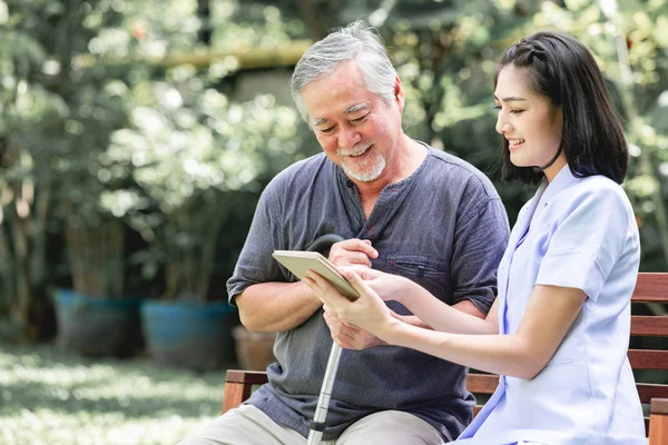 Infirmière Avec Patient Assis Sur Banc Regardant Ensemble Tablette Asiatique — Photo