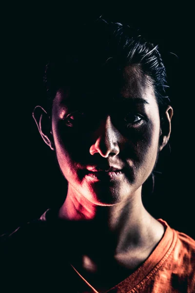 Halloween zombie girl portrait. Asian woman in orange t-shirt, dramatic lighting. For scary halloween concept.
