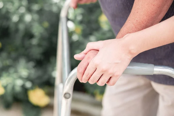 Walker huzur yurdundan kullanarak hasta ile hemşire. Genç kadın holding eski erkek eli açık bahçe yürüme hemşire. Üst düzey bakım, bakım alıcı ve üst düzey emeklilik ev hizmet anlayışı.