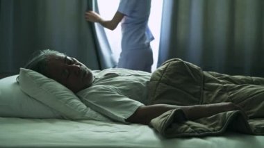 Olgun Asyalı adam hastanede yatıyor gri saçlı hemşire açılış perdeler