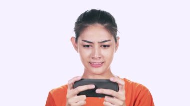 turuncu kazak giyen ve smartphone beyaz arka plan üzerinde oynamaya konsantre Genç Asyalı kadın