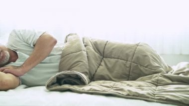 battaniyenin altında yatakta uyuyan gri saçlı Olgun Asyalı adam