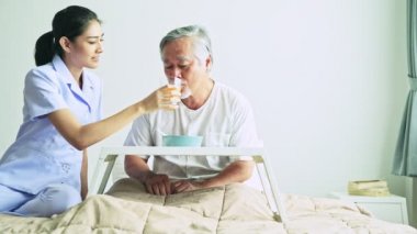 Hastanede gri saçlı gülümseyen olgun Asyalı adam vererek suyu hemşire