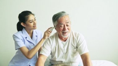 Genç Asyalı hemşire hastanede beyaz t-shirt giyen olgun Asyalı adam Sıcaklığı ölçme