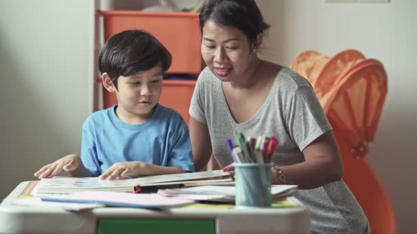 母亲显示儿子图片在书和教学阅读在家里 — 图库视频影像