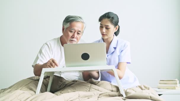 Junge Asiatische Krankenschwester Unterrichtet Erwachsenen Mann Tippen Auf Laptop Drinnen — Stockvideo