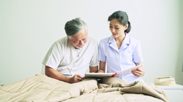 看護師病院で白い シャツを着ているグレーの髪を持つ成熟したアジア人の本を読んで — ストック動画