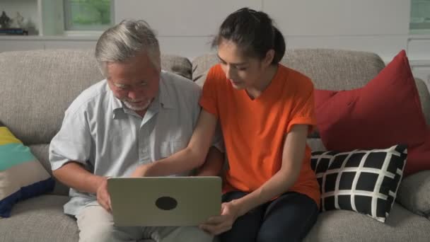 Asiatische Enkelin Lehrt Großvater Laptop Arbeiten Hause Auf Dem Sofa — Stockvideo