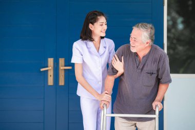 Walker huzur yurdundan kullanarak hasta ile hemşire. Genç kadın kıdemli ev önünde tutan yaşlı adamın omuz hemşire. Üst düzey bakım, bakım alıcı ve üst düzey emeklilik ev hizmet anlayışı.