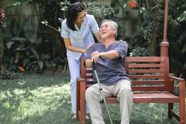 Hemşire ile hasta birlikte konuşurken bankta oturan. Onunla konuşmayı tezgah ve genç kadın bakıcı oturan Asya yaşlı adam. Mutlu bir gülümseme.