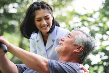 Hemşire ile hasta birlikte konuşurken bankta oturan. Onunla konuşmayı tezgah ve genç kadın bakıcı oturan Asya yaşlı adam. Mutlu bir gülümseme.