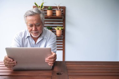 Yaşlı adam bilgisayar açık balkonda kullanılmaya çalışılıyor. Beyaz sakallı, dizüstü bilgisayar kullanarak Asya adam üzgün ruh hali. Üst düzey yaşam tarzı kavramı.
