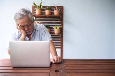 Yaşlı adam bilgisayar açık balkonda kullanılmaya çalışılıyor. Beyaz sakallı, dizüstü bilgisayar kullanarak Asya adam üzgün ruh hali. Üst düzey yaşam tarzı kavramı.