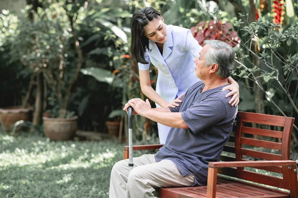 Hemşire ile hasta birlikte konuşurken bankta oturan. Asyalı yaşlı adam ve birlikte konuşurken oturan bir genç bayan. Ruh sakin ol.