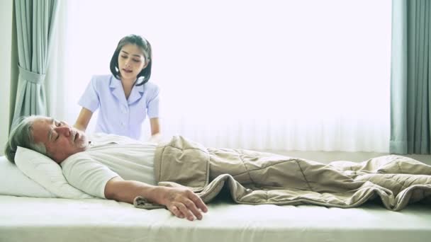 グレーの髪を持つ成熟したアジアの男を助ける若い看護師が病院で朝起きる — ストック動画