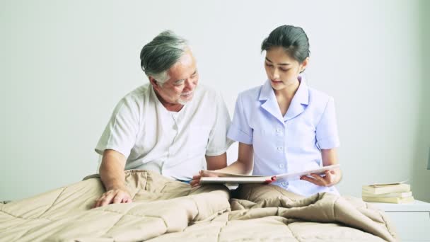 Young Nurse Reading Book Mature Asian Man Grey Hair Hospital — Stock Video