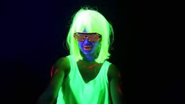 Güzel seksi kadın giyim kamera önünde dans parlayan Uv yüz boyama, peruk, ile. Beyaz kadın. Parti konsept.