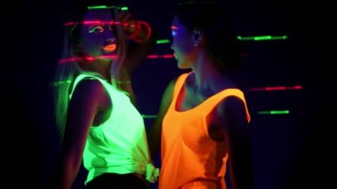 Uv ile güzel seksi kadın giyim birlikte yarım vücut shot kamera önünde dans parlak bilezikler, parlak boya, yüz. Beyaz ve Asyalı bir kadın. Parti konsept.