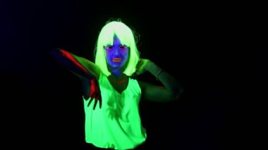 Güzel seksi kadın ile Uv yüz boyama, peruk, giyim kamera önünde, yarım vücut ateş dansı parlayan. Beyaz kadın. Parti konsept.