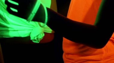 Güzel seksi kadın Uv yüz boyama, parlayan giyim, parlak bilezik, kamera önünde dans gözlük ile vuruş. Kafkas ve kadın. Parti konsept.