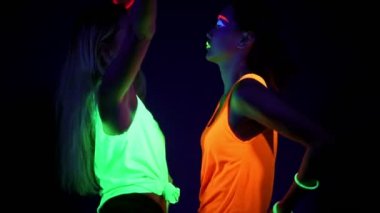 Uv ile güzel seksi kadın giyim birlikte yarım vücut shot kamera önünde dans parlak bilezikler, parlak boya, yüz. Beyaz ve Asyalı bir kadın. Parti konsept.