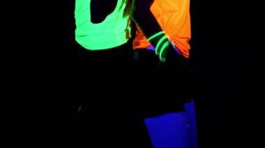 Bilezikler, parlayan gözlük, parlayan güzel seksi kadın ile Uv yüz boyama, vücut orta kamera önünde birbirlerine karşı geri giyim dans vurdu. Beyaz ve Asyalı bir kadın. Parti konsept.