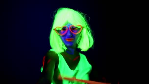 フェイス ペイント かつら 光る眼鏡 化学スティックがカメラの前で踊る美しいセクシーな女性 白人女性 パーティー コンセプト — ストック動画