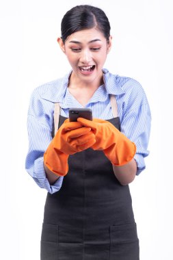 Ev temizlik hizmeti kadın beyaz izole. Asyalı Genç Kadın eldivenler, kullanma cep telefonu ile büyük sürpriz poz. Online ev temizlik hizmeti kavramı.