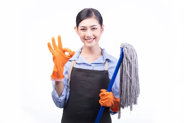 房屋清洁服务妇女查出的白色 亚洲年轻妇女与手套 快乐的微笑 持有拖把 好姿势 房屋清洁服务概念 图库图片
