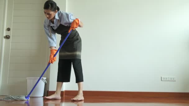 Woman cleaning house with a mop. Beautiful Asian woman cleaning floor with mop. Low angle shot. House cleaning service concept.
