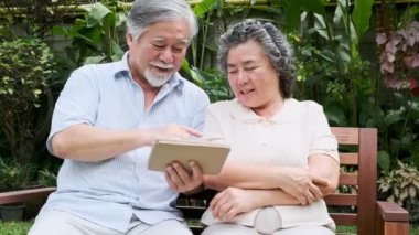 Oturma ve kullanarak üst düzey çift birlikte ev bahçesinde tablet. Emekli eski Asya erkek ve kadın, tablet, mutlu gülümseme haber okumak. Üst düzey yaşam tarzı kavramı. 