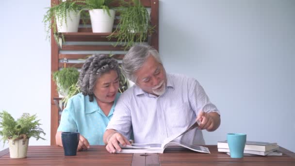 资深夫妇一起坐在阳台上看书 退休的老亚洲男女 一起看书 快乐的微笑 老年人生活方式理念 — 图库视频影像