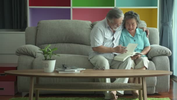 Senior Couple Sitting Reading Book Together Living Room Retired Old — Stock Video