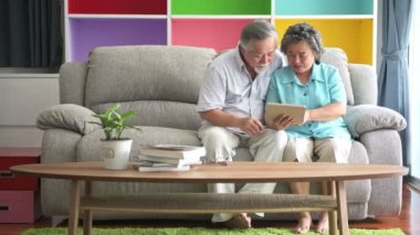 Üst düzey iki oturma ve tablet oturma odasında izliyor. Emekli eski Asya erkek ve kadın, oturma odası kanepe, mutlu gülümseme tablet oynamaktan zevk. Üst düzey yaşam tarzı kavramı.