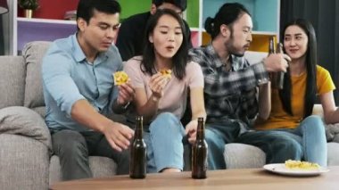 Pizza yeme ve koltukta bira içme arkadaş grubu. Pizza ve bira birlikte zevk, tezahürat ve eylem kızartma karışık yarış genç insanlar. Ev partisi konsepti. 