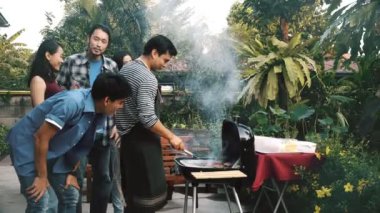 Arkadaşlar Barbekü Izgara açık ham hamburger pişirmek için çalışıyor. Grup Asya, beyaz genç adam ve barbekü ızgara duran, gülen ve having fun ile birlikte kadın yanık et. Ev partisi konsepti.