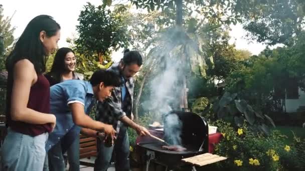 朋友们试图在户外的 Bbq 烧烤中煮生汉堡 一群亚洲人 高加索青年男女站在 Bbq 笑着和燃烧的肉一起玩 众议院党概念 — 图库视频影像