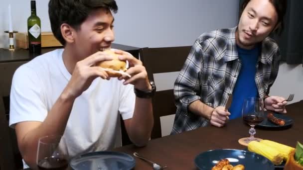 Amigos Cenando Una Fiesta Casa Hombre Asiático Degustando Una Hamburguesa — Vídeo de stock