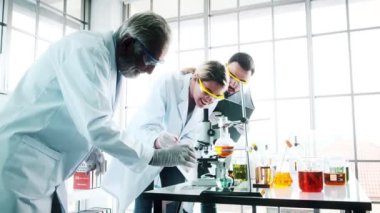Bir laboratuarda çalışan kimyagerler grubudur. Beyaz genç erkek ve dişi kimyagerler ile mikroskop arıyorum birlikte laboratuarda, çalışan üst düzey beyaz kimyager. Bilim kavramı.