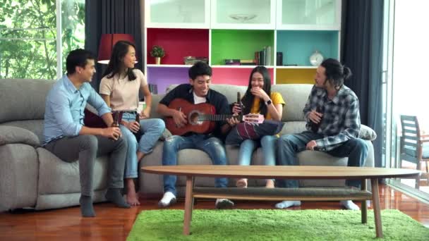 一群朋友正在家里庆祝聚会 人们坐在坐在坐在一边喝着啤酒 男人弹吉他 而男人和女人唱歌 — 图库视频影像