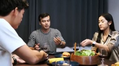 Arkadaşlar ev partisinde yemek yiyor. Karışık ırk gençler birlikte akşam yemeği ve şarap zevk, birlikte konuşmak ve burger yemek. House parti kavramı.