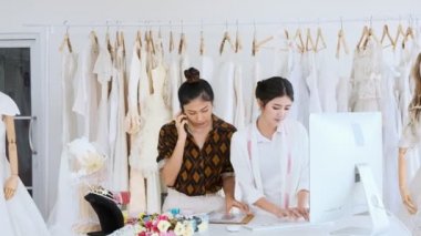 Birlikte çalışan genç moda evi tasarımcı. Gelin elbise, Evet ve müşteriler emir alan genç Asyalı kadın ile bilgisayar. Küçük işletme kavramı.