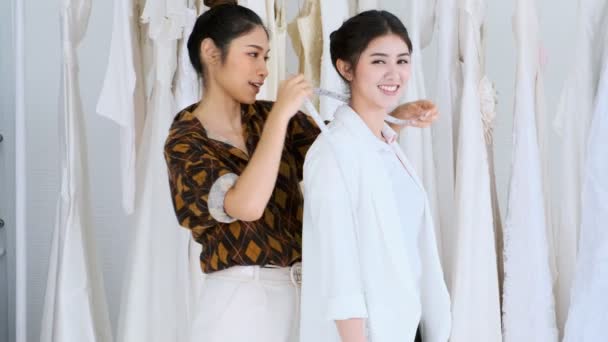 若い結婚式ドレス デザイナー作業 若いアジア女性のウェディング ドレスの彼女の顧客の体を測定します スモール ビジネス コンセプト — ストック動画